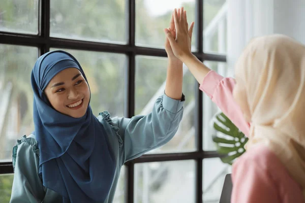 Two hijab Asian women clapping hands together as congratulation after successfully working together. run by a young, talented woman. Management concept runs the company female leaders to grow company.