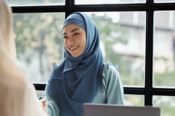 Two hijab Asian women shaking hands after a startup company meeting. run by a young, talented woman. The management concept runs the company of female leaders to grow the company.