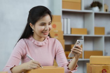 Online store salesperson is writing a customer's shipping address on parcel box before sending it to private carrier for delivery to customer. The idea of opening an online store and packing products.