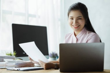 Beautiful Asian woman working with computers in the office of a startup company, she is a company finance employee working in the finance department. Concept of women working in a company.