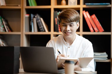 A man sits in the office of a startup company, he is an employee working in the marketing department, planning marketing to grow the company. Concept of working in a startup company office.