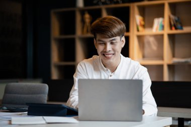A man sits in the office of a startup company, he is an employee working in the marketing department, planning marketing to grow the company. Concept of working in a startup company office.