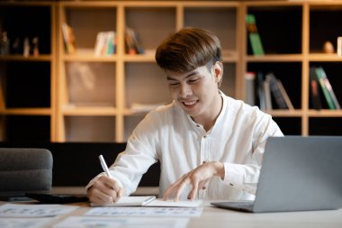 A man sits in the office of a startup company, he is an employee working in the marketing department, planning marketing to grow the company. Concept of working in a startup company office.