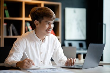 A man sits in the office of a startup company, he is an employee working in the marketing department, planning marketing to grow the company. Concept of working in a startup company office.
