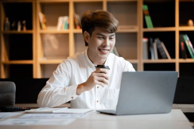 A man sits in the office of a startup company, he is an employee working in the marketing department, planning marketing to grow the company. Concept of working in a startup company office.