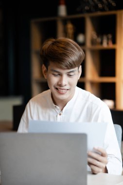 A man sits in the office of a startup company, he is an employee working in the marketing department, planning marketing to grow the company. Concept of working in a startup company office.