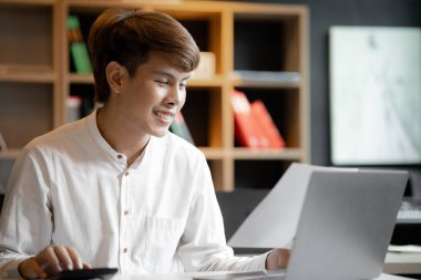 A man sits in the office of a startup company, he is an employee working in the marketing department, planning marketing to grow the company. Concept of working in a startup company office.