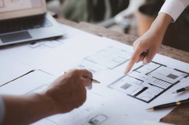 Two architects and engineers are in a meeting to discuss and inspect the house designs to meet the building and construction standards. Interior design and decoration ideas.