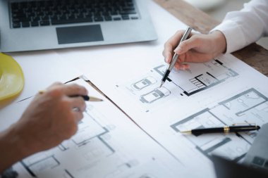 Two architects and engineers are in a meeting to discuss and inspect the house designs to meet the building and construction standards. Interior design and decoration ideas.