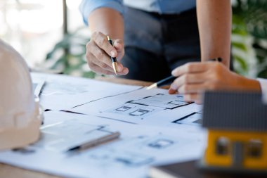 Two architects and engineers are in a meeting to discuss and inspect the house designs to meet the building and construction standards. Interior design and decoration ideas.