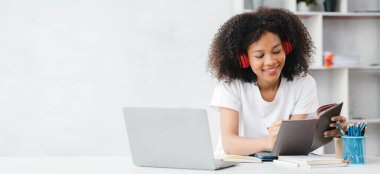 Beyaz odadaki Amerikalı kadın, o bir üniversite öğrencisi, evinde online çalışıyor, videoyla çalışıyor ve ev ödevlerini yapıyor. İnternet 'te okuyan öğrenciler konsepti.