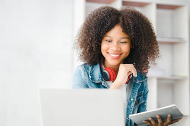 Beyaz odadaki Amerikalı kadın, o bir üniversite öğrencisi, evinde online çalışıyor, videoyla çalışıyor ve ev ödevlerini yapıyor. İnternet 'te okuyan öğrenciler konsepti.