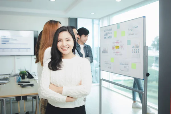 一名亚洲妇女与她的胳膊交叉在一家初创公司的会议室里 她是国际营销部门的一名公司员工 她参加了一个公司的会议 — 图库照片