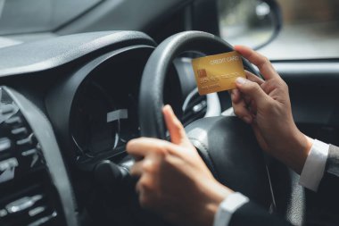 Resmi takım elbiseli Asyalı bir adam arabada, bir kredi kartı tutuyor, bir benzin istasyonuna gidiyor ve kredi kartı faturalarını ödüyor, arabayla seyahat ediyor, güvenli sürüş, trafik kurallarına saygı duyuyor..