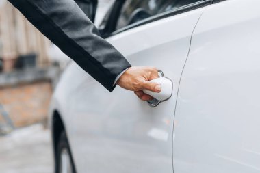 İşe gitmek için araba kapısı açan bir adam, yolda güvenli bir şekilde seyahat etmek ve trafik kurallarına uymak için araçları kullanıyor. Güvenli sürüş kavramı.