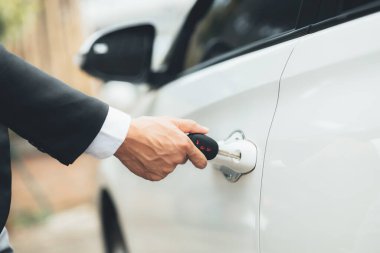 Adam işe gitmek için araba kapısını açmak için araba anahtarı kullanıyor, yolda güvenli bir şekilde seyahat etmek ve trafik kurallarına uymak için araçları kullanıyor. Güvenli sürüş kavramı.