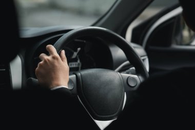 Takım elbiseli bir adam işe giderken araba kullanıyor, şirkette işe giderken de araba kullanıyor. Araç kullanma kavramı.