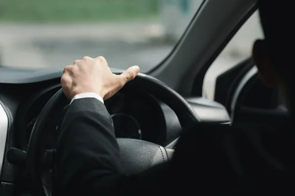 A man in a suit is driving a car to work, he is driving a car to work at the company. Vehicle driving concept.
