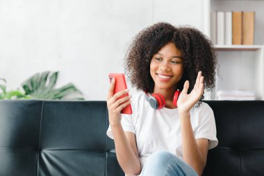 Amerikalı bir kadın cep telefonuyla koltukta oturur, arkadaşlarıyla video görüşmeleri yapar, hafta sonunu sosyal medyada geçirir, film izler ve evde müzik dinler. Tatil kavramı.