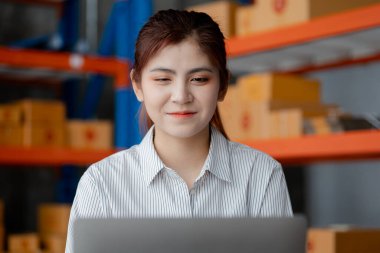 Güzel bir Asyalı işletme sahibi online bir dükkan açıyor, müşterilerin siparişlerini kontrol ediyor, bir kurye şirketi aracılığıyla mal gönderiyor, bir kadının online iş kurma kavramı.