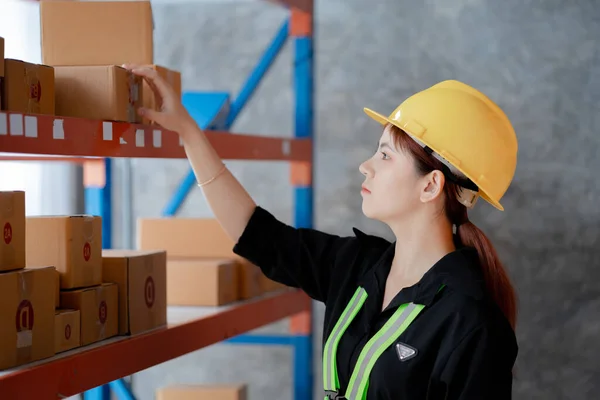 安全服を着たアジアの女性労働者が倉庫にいて 出荷前に倉庫の商品をチェックしています 倉庫で働くことと倉庫で働くことのコンセプトは安全です — ストック写真
