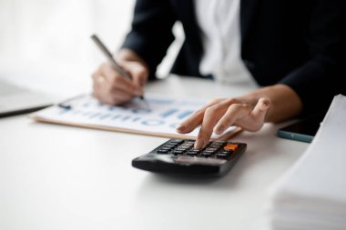 Businessman using a calculator to calculate numbers on a company's financial documents, he is analyzing historical financial data to plan how to grow the company. Financial concept.