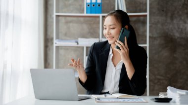 Güzel Asyalı kadın yöneticiler, işletme yöneticileri, pazarlama yöneticileri pazarlama için şirketle iletişime geçmek üzere müşterilerle telefonda konuşuyorlar. Pazarlama yönetimi kavramı.