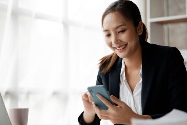 İşe ara verdiğinde cep telefonuyla oynayan güzel bir Asyalı kadın. Yeni başlayan bir şirketin pazarlama müdürü, kadın lider, yönetici ve CEO 'su. Kadın Liderlik Konsepti.