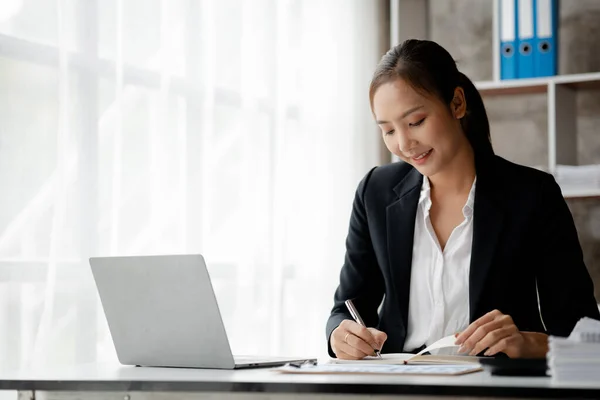 A businesswoman is checking company financial documents and using a tablet to talk to the chief financial officer through a messaging program. Concept of company financial management.