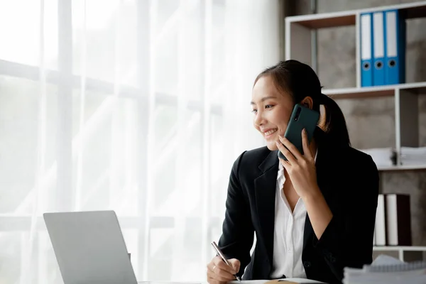 Beautiful Asian woman executives, business executives, marketing executives are talking on the phone with customers to contact the company for marketing. Marketing management concept.