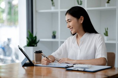 Asian woman working on laptop, female employee of a marketing company, she is working on a marketing plan for a company to generate income and profit, grow sales. Marketing planning concept.