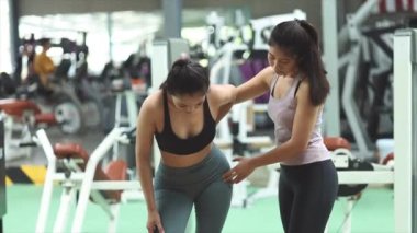 İki kadın spor salonunda antrenman yapıyor, bayan antrenör müşterileri egzersizlerle çalıştırıyor, egzersiz yapmadan önce ısınıyor ve sağlık hizmetleri için fitness merkezine gidiyor. Fitness eğitim konsepti.