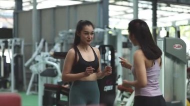 Spor salonunda antrenman yapan iki kadın, bir bayan antrenör ve bir müşteri eğitim programının detaylarını, nasıl forma girip kilo verilebileceğini açıklamak için spor salonunda sohbet ediyorlar. Fitness eğitim konsepti.