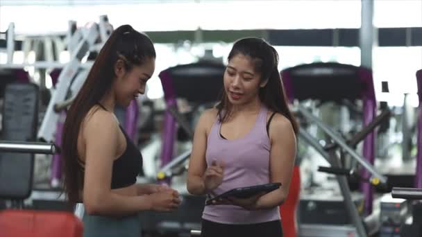 Две Женщины Тренируются Фитнес Центре Женщина Тренер Клиент Беседуют Тренажерном — стоковое видео