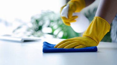 Odayı temizleyen kişi, temizlik personeli şirket odasındaki masaları silmek için dezenfektan ve bez kullanıyor. Temizlik personeli. Organizasyondaki temizliği sürdürmek.