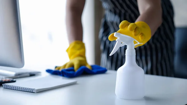 Person cleaning the room, the cleaner is wiping the desk in the company office. Cleaning staff. Concept of cleanliness in the organization.