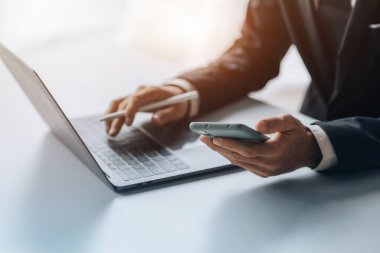 Business man looking at financial information from a mobile phone, he is checking company financial documents, he is an executive of a startup company. Concept of financial management.