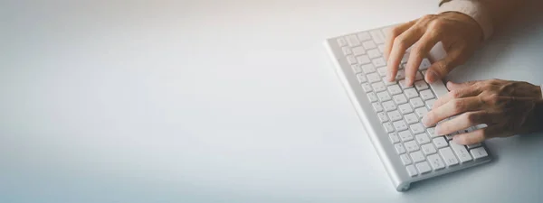 Person typing on a computer keyboard, businessman is working in a startup company\'s office, he is typing messages to his colleagues and making financial documents summarizing the meetings. Copy space.