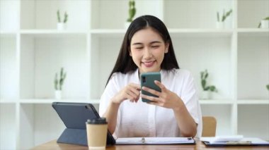 Cep telefonundan mali bilgilere bakan genç bir iş kadını, şirketin mali belgelerini kontrol ediyor, yeni kurulan bir şirketin kadın yöneticisidir. Mali yönetim kavramı.