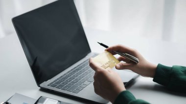 Woman holding a credit card, she uses a credit card to pay for goods and services online, the concept of using a credit card for online shopping, ordering goods and services on the website.