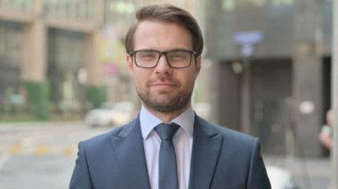 Caddede dikilirken kameraya gülümseyen iş adamının portresi