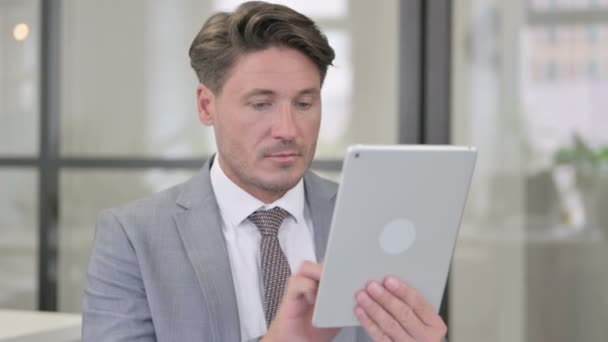Привабливий чоловік середнього віку використовує планшет в офісі — стокове відео