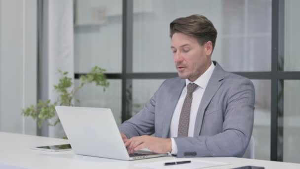 Mann mittleren Alters zeigt bei der Arbeit mit Laptop Daumen-runter-Zeichen — Stockvideo