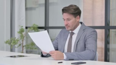 Ofiste Otururken Orta Yaşlı Adam Belgeleri Okuyor