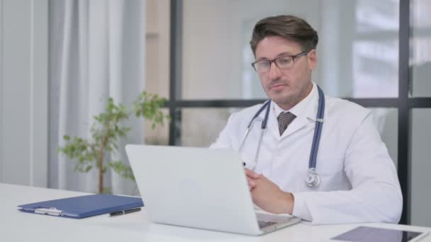 Доктор говорит на видео-звонок на ноутбуке в клинике — стоковое видео