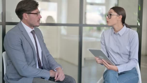 Junge Frau mit Tablet interviewt Geschäftsmann mittleren Alters — Stockvideo