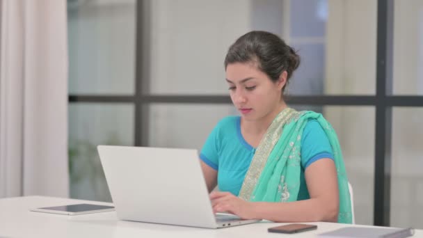 Индийская женщина качает головой без каких-либо признаков при использовании ноутбука в офисе — стоковое видео