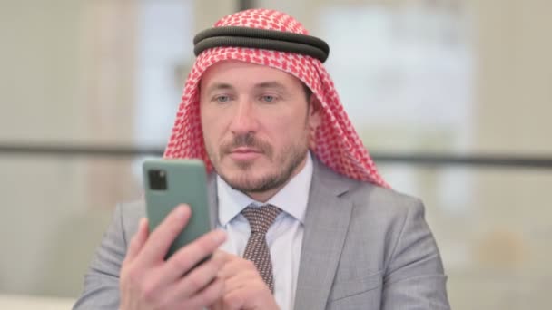 Retrato del hombre de negocios árabe de mediana edad celebrando en el teléfono inteligente — Vídeos de Stock