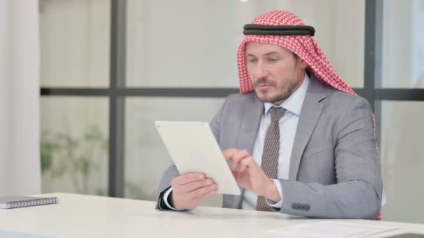 事務所に座っている間にタブレットを使用している中年アラブビジネスマン — ストック動画