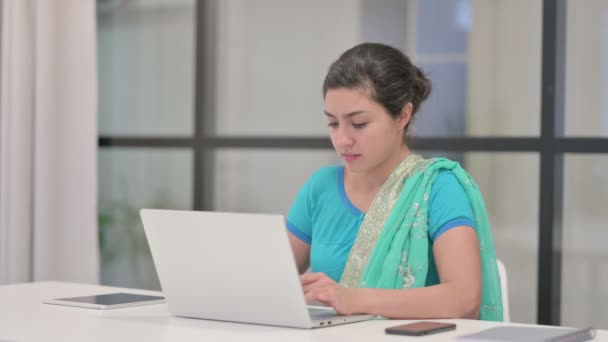 Индийская женщина смотрит в камеру, пользуясь топом в офисе — стоковое видео